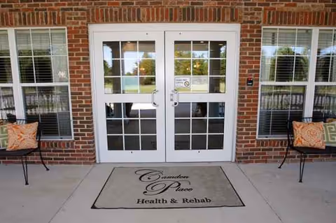 Exterior entrance of Camden Health and Rehabilitation with brick facade, glass doors, and a welcome mat.