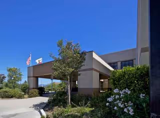 Exterior front of Vibra Hospital of Northern California with flags and landscaping.