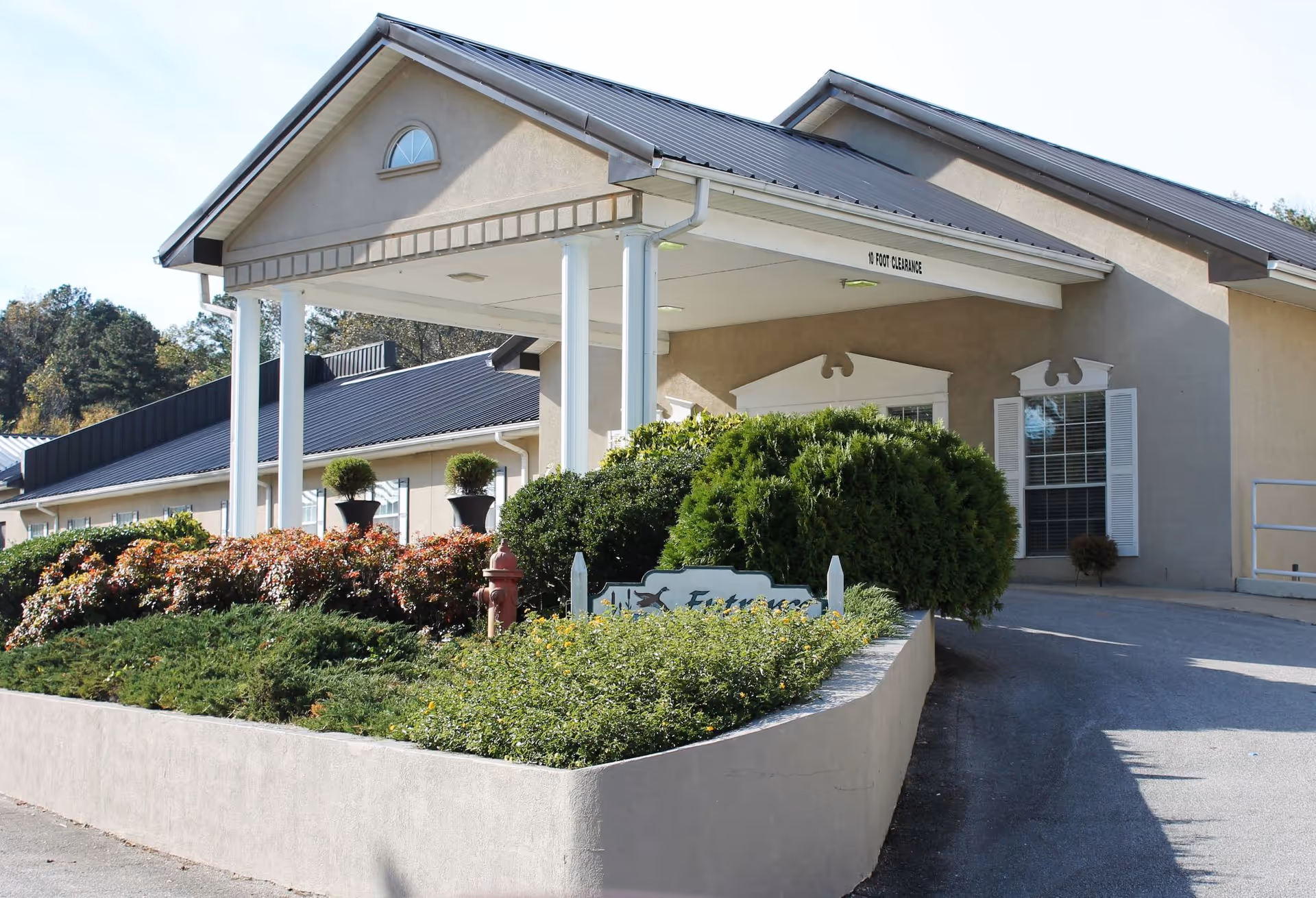Entrance and porte-cochere of the Village at Cook Springs with landscaped flowerbeds and shrubs in front.