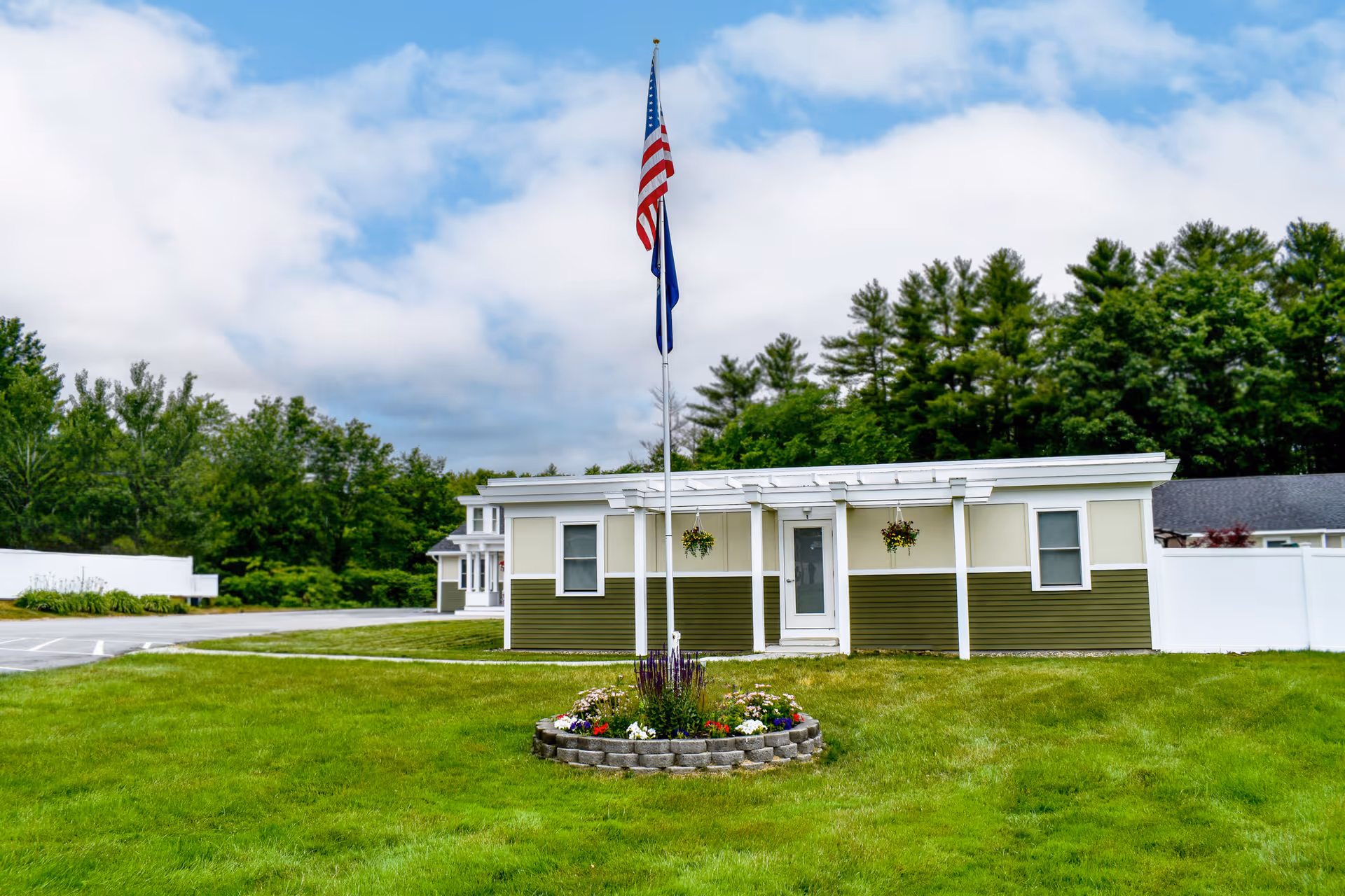 Exterior view of The Lamp Memory Care Center featuring a building with a flag and landscaped area.