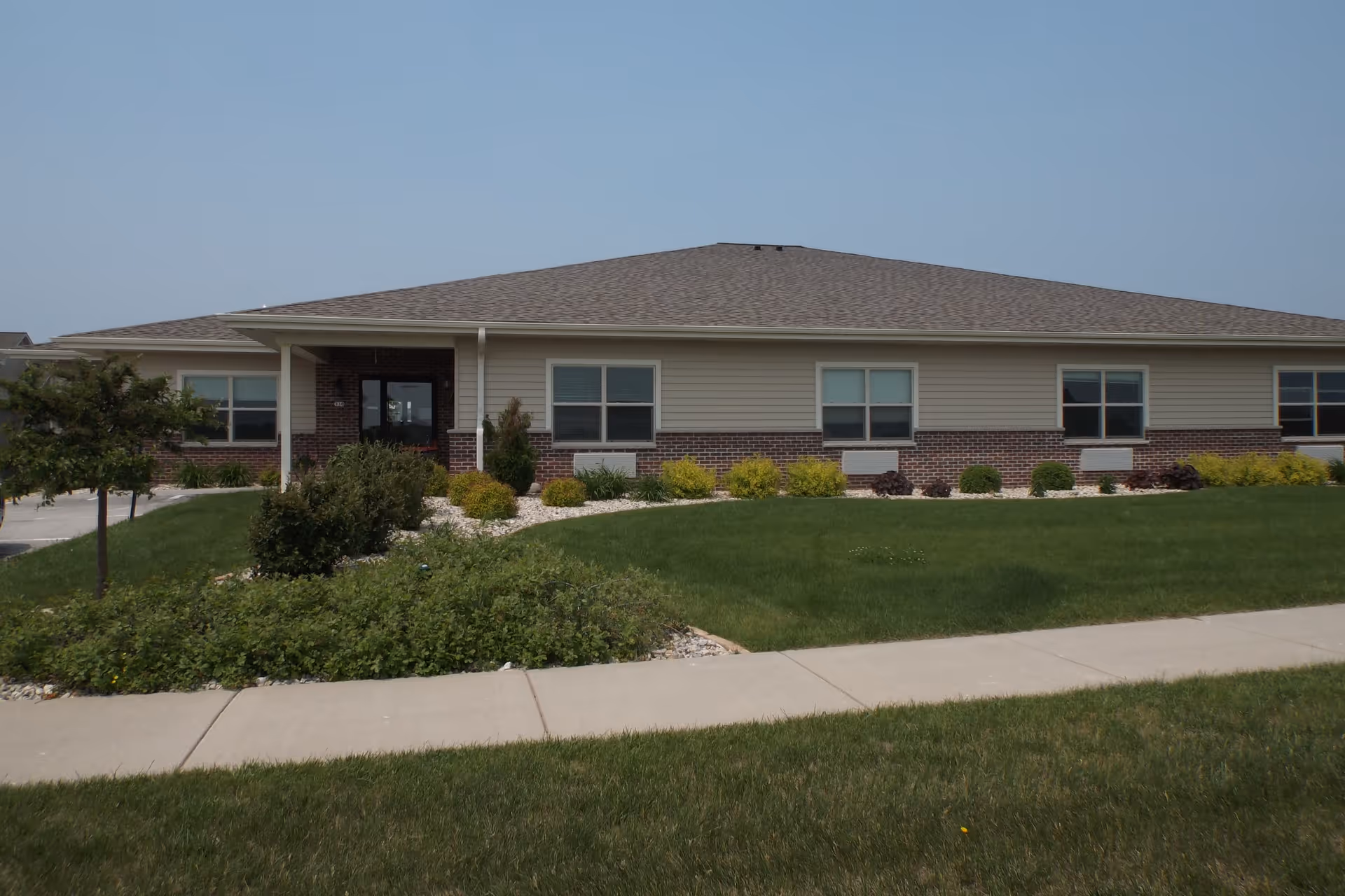 Single-story brick-and-siding building with a covered entrance, landscaped lawn and a sidewalk in front.