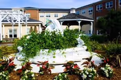 Front view of Beth Sholom Village exterior with a decorative fountain and landscaped garden.
