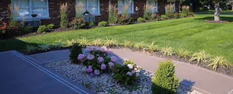 Front view of Seymour Crossing exterior with green lawn, shrubs, and flowering plants.