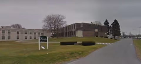 Exterior view of RiverLedge Residence with sign, driveway, and lawn.