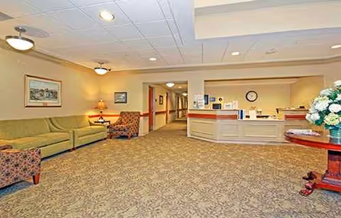 Lobby area with reception desk, seating, and hallway in a senior facility.