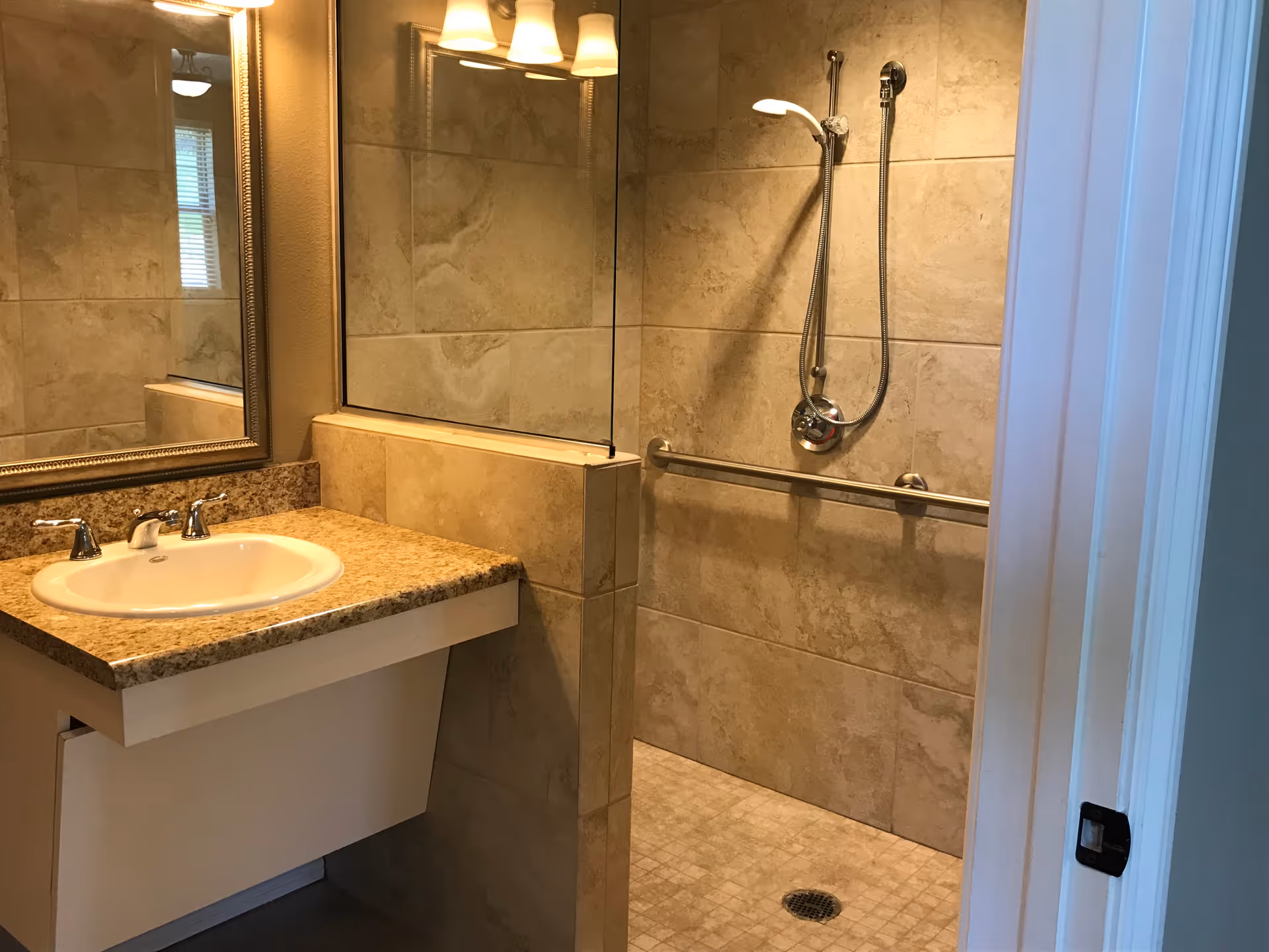 Bathroom with granite countertop sink, large mirror, tile walls, and a walk-in shower.