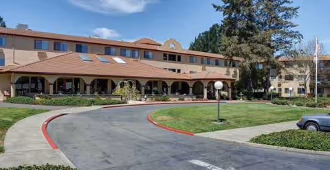 Wide view of Holiday Redwood facility front with curved driveway and arched entrance.