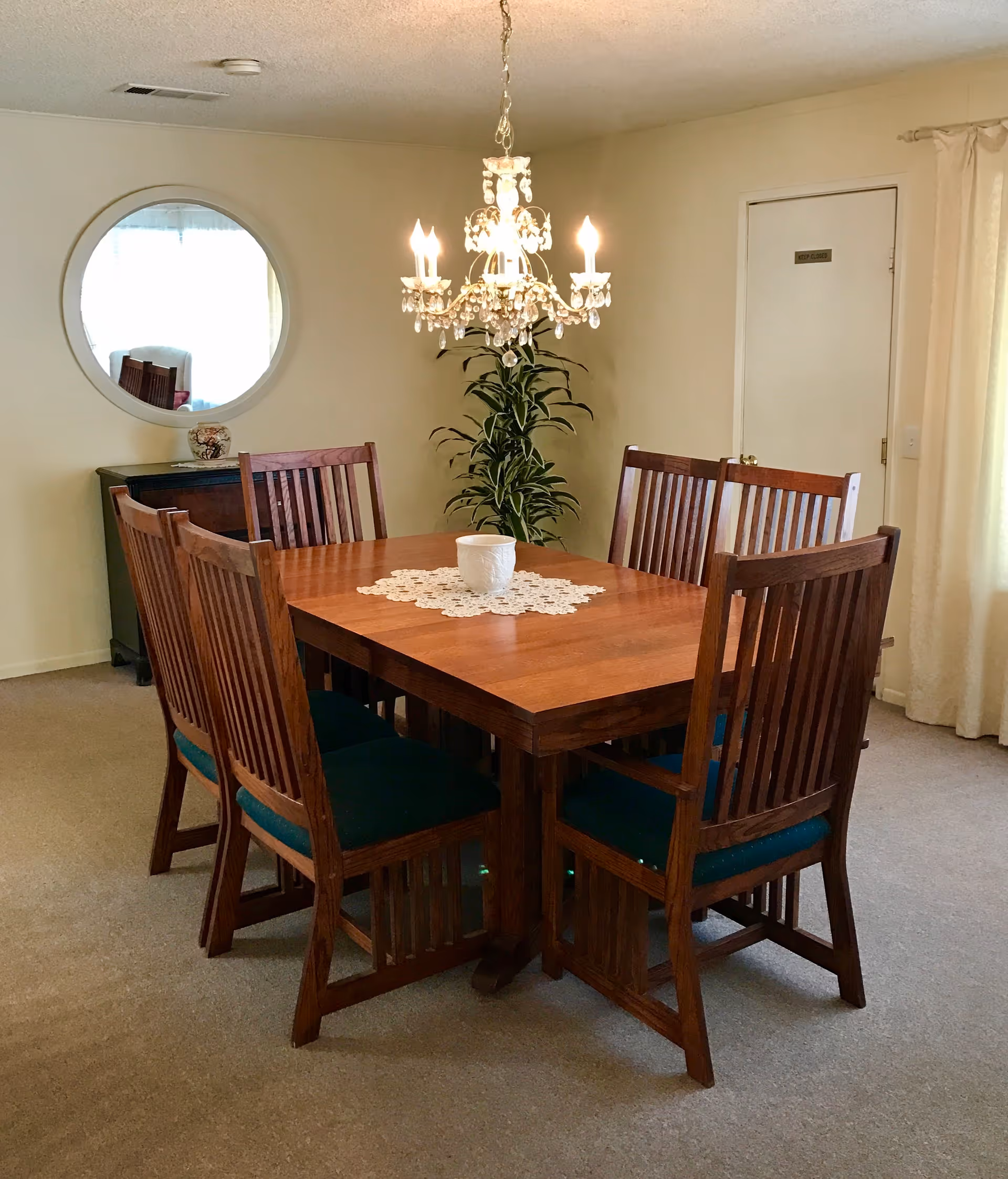 A wooden dining table with six chairs and a chandelier in a cozy residential dining room.