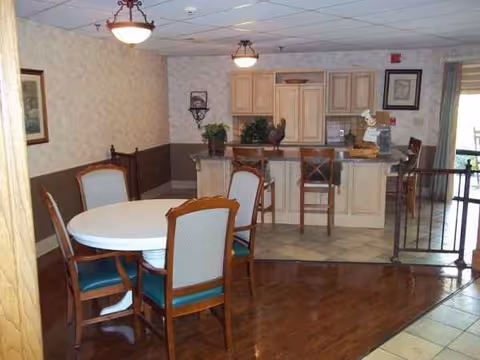 Interior dining area with a round table and chairs, kitchen counter and cabinets in back.