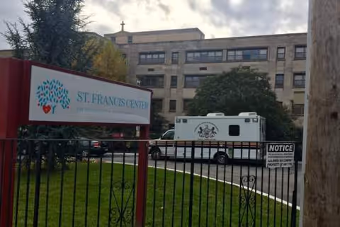 Exterior view of St. Francis Center building with sign and parked vehicle.