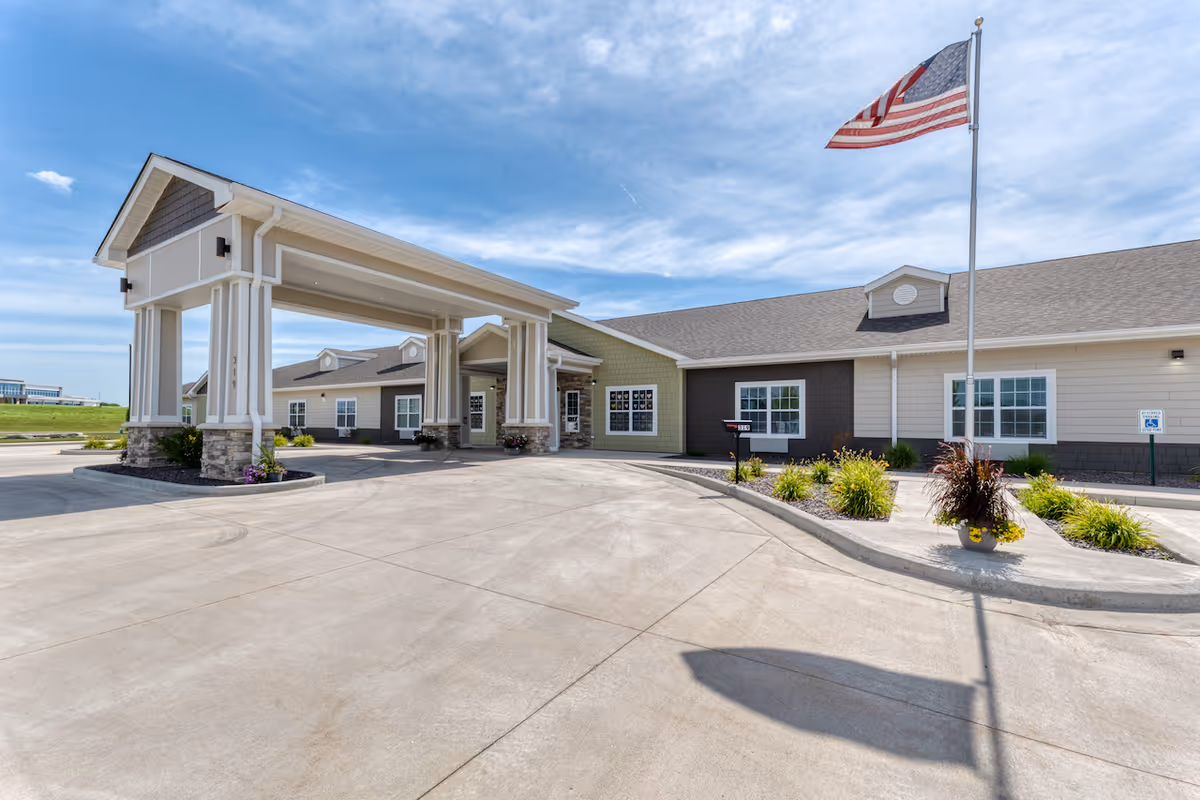 Exterior view of High Point Residence Quincy assisted living facility with porte-cochere and flag