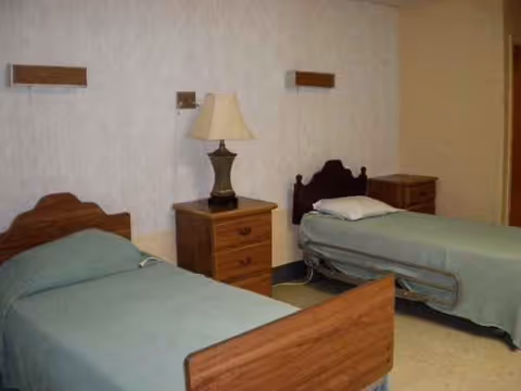 Two single beds with matching wooden headboards and a nightstand with lamp in a clean bedroom.
