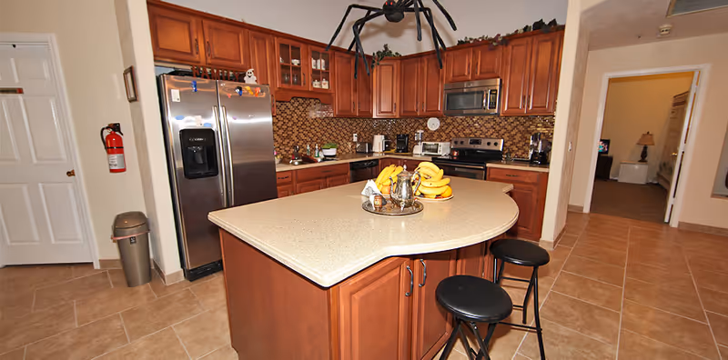 Modern kitchen with wooden cabinets, stainless appliances, and a curved island.