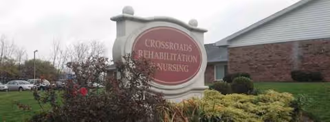 Exterior view of Crossroads Rehabilitation & Nursing with a circular sign and landscaping.