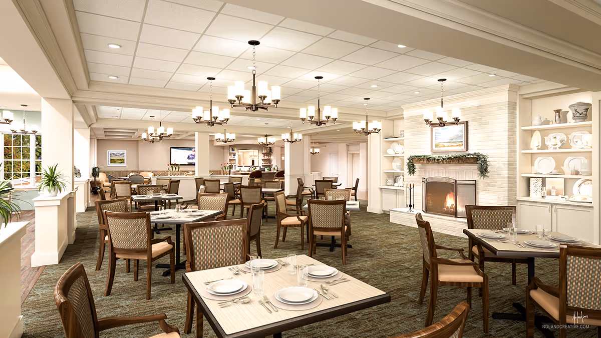 A spacious dining room in a senior living facility with multiple tables set with plates, glasses, and silverware. The room features patterned carpet, wooden chairs with cushioned seats, several chandeliers hanging from the ceiling, a fireplace with a painting above it, and built-in shelves displaying decorative plates and vases. Large windows on the left side allow natural light to enter the room.