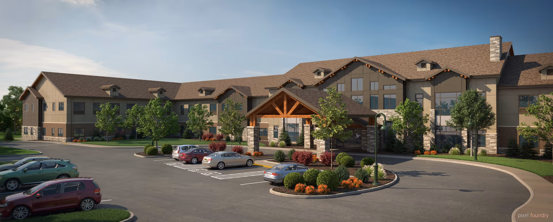 Exterior view of a large two-story assisted living facility with a covered entrance, multiple windows, landscaped greenery, and a parking lot with several cars parked.