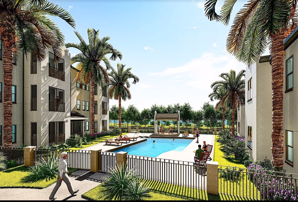 Outdoor view of a senior living facility courtyard featuring a swimming pool surrounded by lounge chairs and palm trees. Several people are enjoying the pool and sitting on chairs near the pool. The area is fenced and landscaped with grass and shrubs, with multi-story residential buildings on either side.