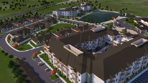 Aerial view of the Spring Cypress Senior Living campus with multi-story residential buildings, landscaped grounds, parking areas, and a central pond.