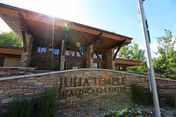 Exterior view of Julia Temple Healthcare Center building entrance with a stone sign displaying the facility's name, surrounded by greenery and a flagpole nearby under a clear sky.