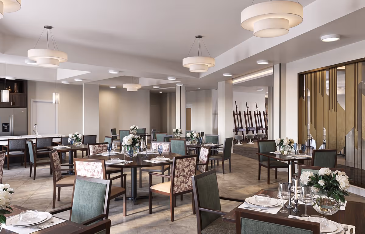 Bright modern dining room with multiple set tables and chairs, floral centerpieces, and pendant lighting.