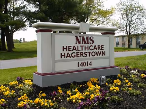 Outdoor front sign for NMS Healthcare Hagerstown surrounded by flowers.