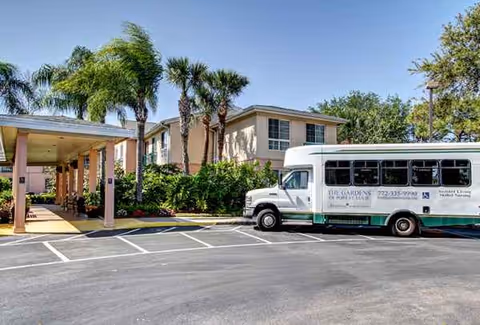 Exterior view of The Gardens of Port St. Lucie with a shuttle bus parked.