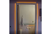 View through a doorway into a bathroom with a toilet, grab bar, towel on a hook, and tiled floor.