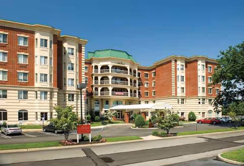 Exterior view of The Bristal Assisted Living at East Meadow, a multi-story red-brick building.