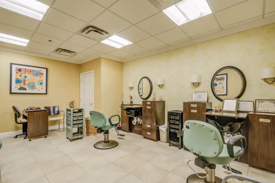Interior salon room with styling chairs, wash basins, mirrors, and cabinets.