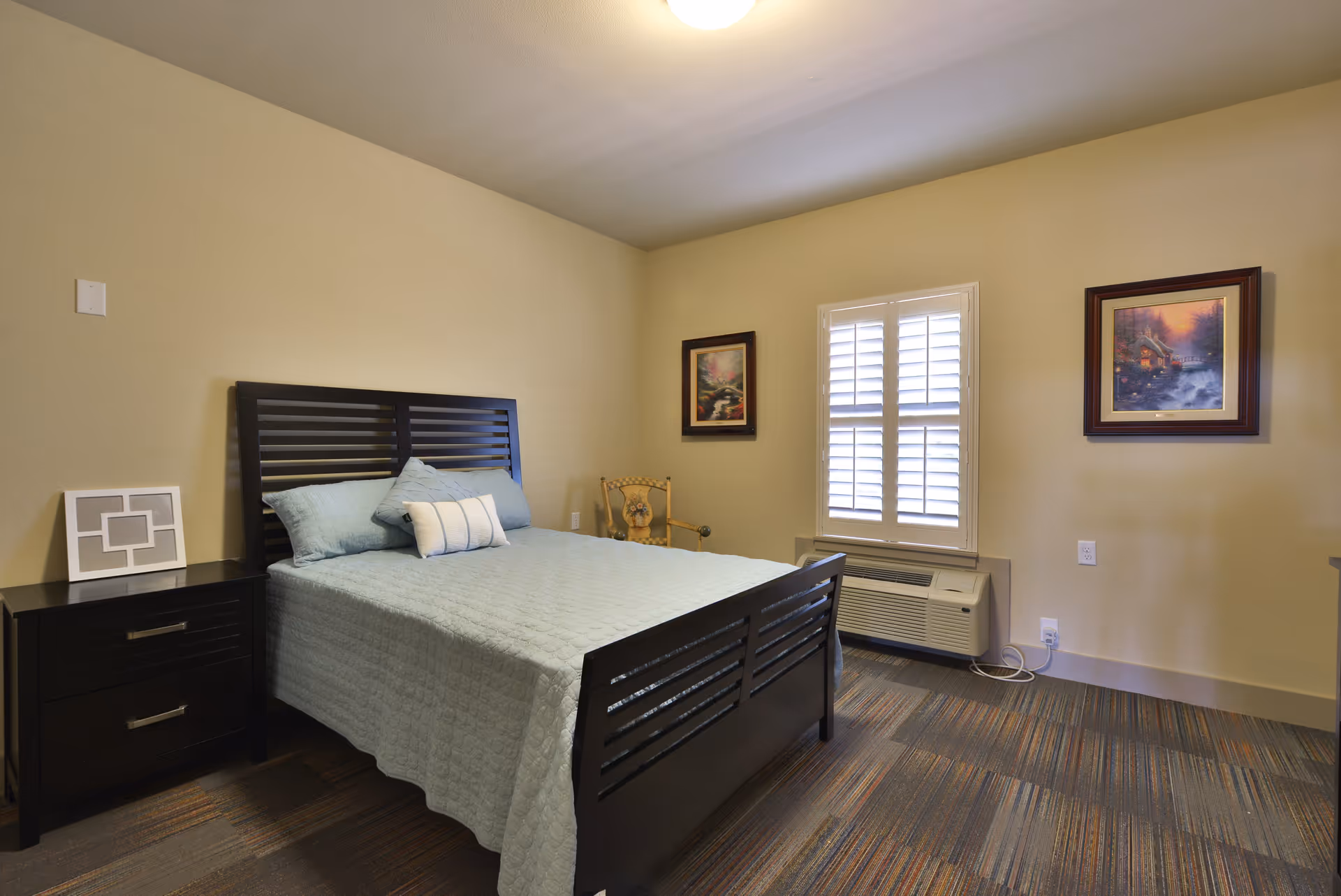 A tidy bedroom with a dark wood bed, matching nightstands, and a window with blinds.