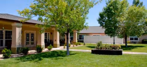 Exterior view of Brookdale Las Vegas entrance with columns, trees, and lawn.