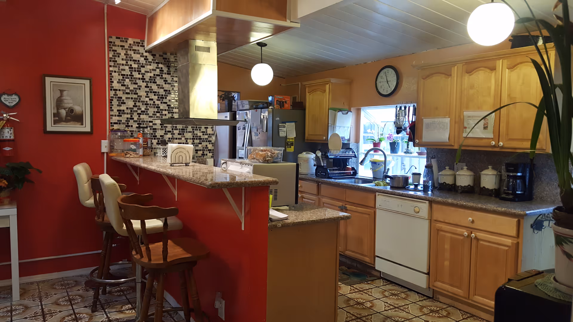 A cozy kitchen area featuring wooden cabinets, bar stools, and a colorful backsplash.