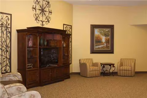 Lounge area with beige walls, striped chairs, a wood cabinet, and a painting.
