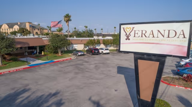 Exterior view of the Veranda Rehabilitation and Healthcare building, its large roadside sign, parking lot, and an American flag.