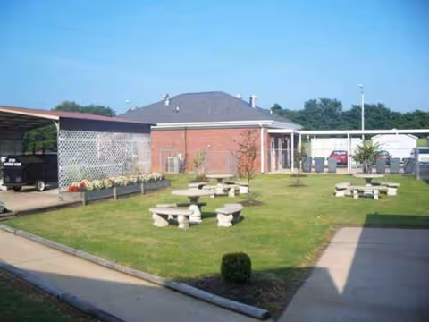 Outdoor courtyard of Dyer Nursing and Rehabilitation Center with grassy lawn and concrete picnic tables.