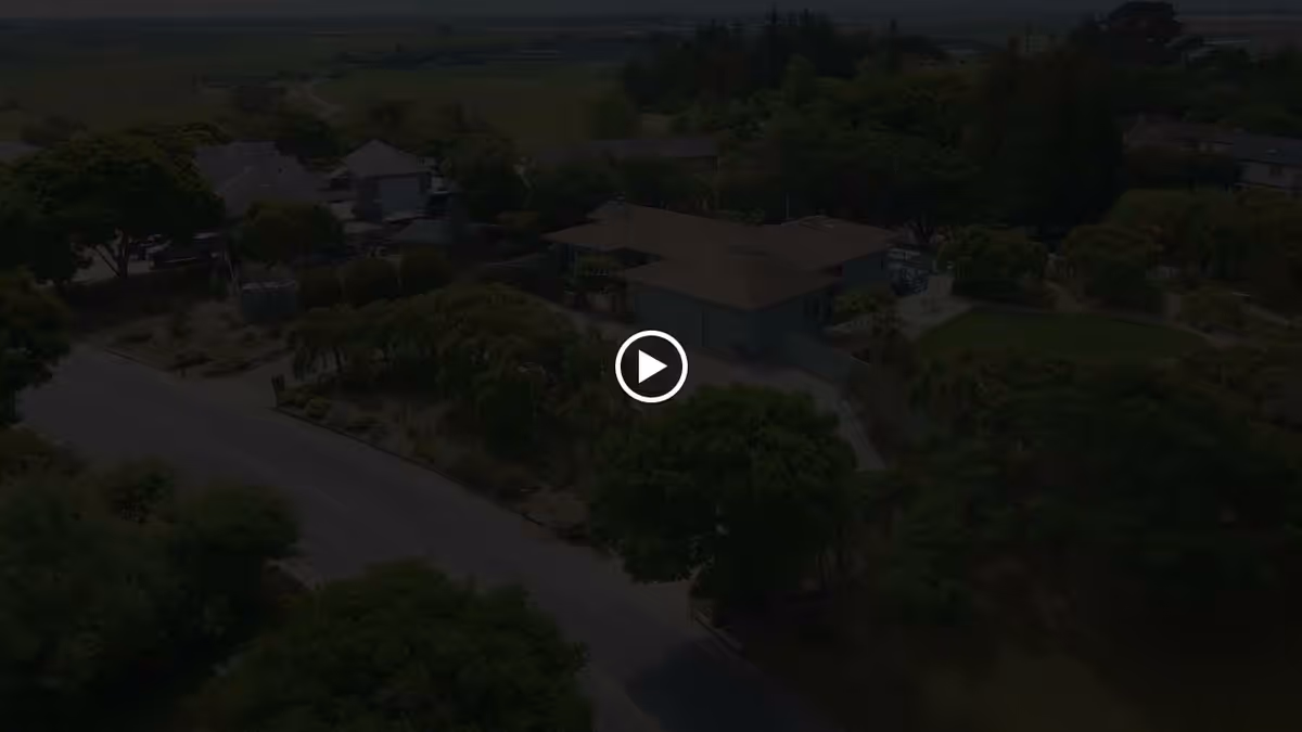 Aerial view of residential buildings and landscaped grounds with trees alongside a curved road.