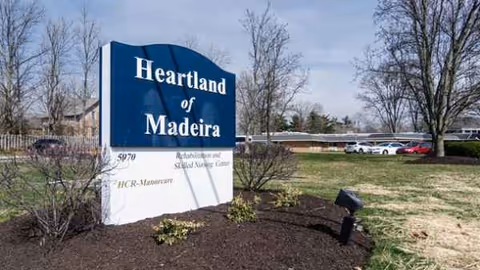 Blue Heartland of Madeira sign with landscaping and parked cars outside the facility.