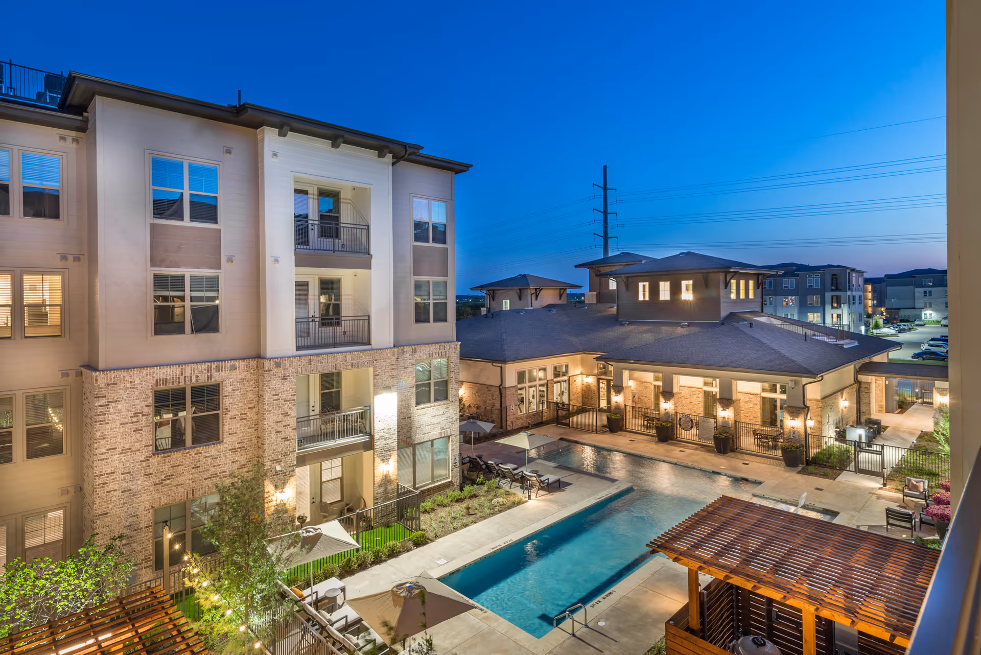 Evening view of a multi-story senior living building overlooking a well-lit courtyard with a swimming pool and seating areas.