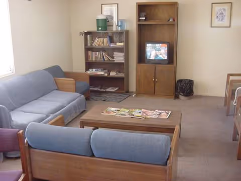 Cozy living room with blue upholstered sofas, coffee table, bookshelf, and a small TV.