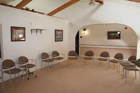 Beige chairs are arranged in a circle in a quiet senior living common area.