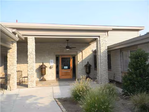 Stone-walled entrance of Charleston Manor with a covered front porch and surrounding landscaping.