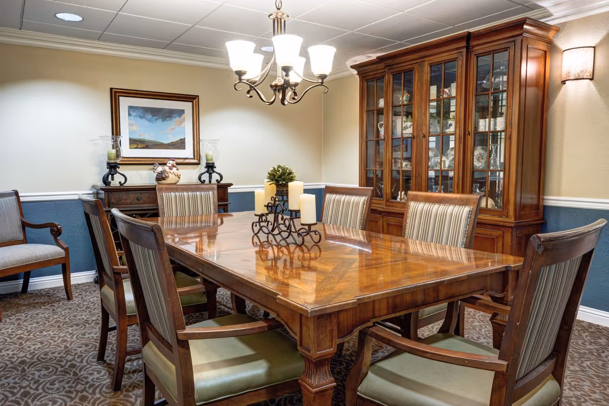 A formal dining room with a wooden table and chairs, a chandelier overhead, and a glass-front china cabinet.