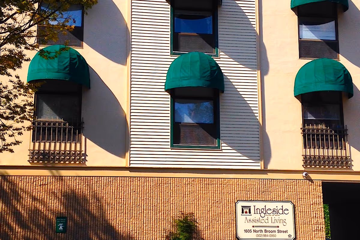 Exterior view of Ingleside Homes Assisted Living LLC building showing three windows with green awnings and a sign with the facility's name and address at 1605 North Broom Street.
