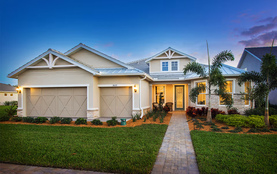 Front exterior view of a single-story house with a three-car garage, a paved walkway leading to the front door, well-maintained green lawn, palm trees, and landscaping under a clear blue sky at dusk.