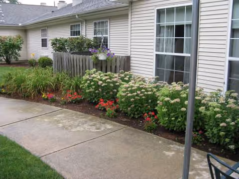 Exterior view of Arden Courts Wayne with a walkway and flowering shrubs along the building.