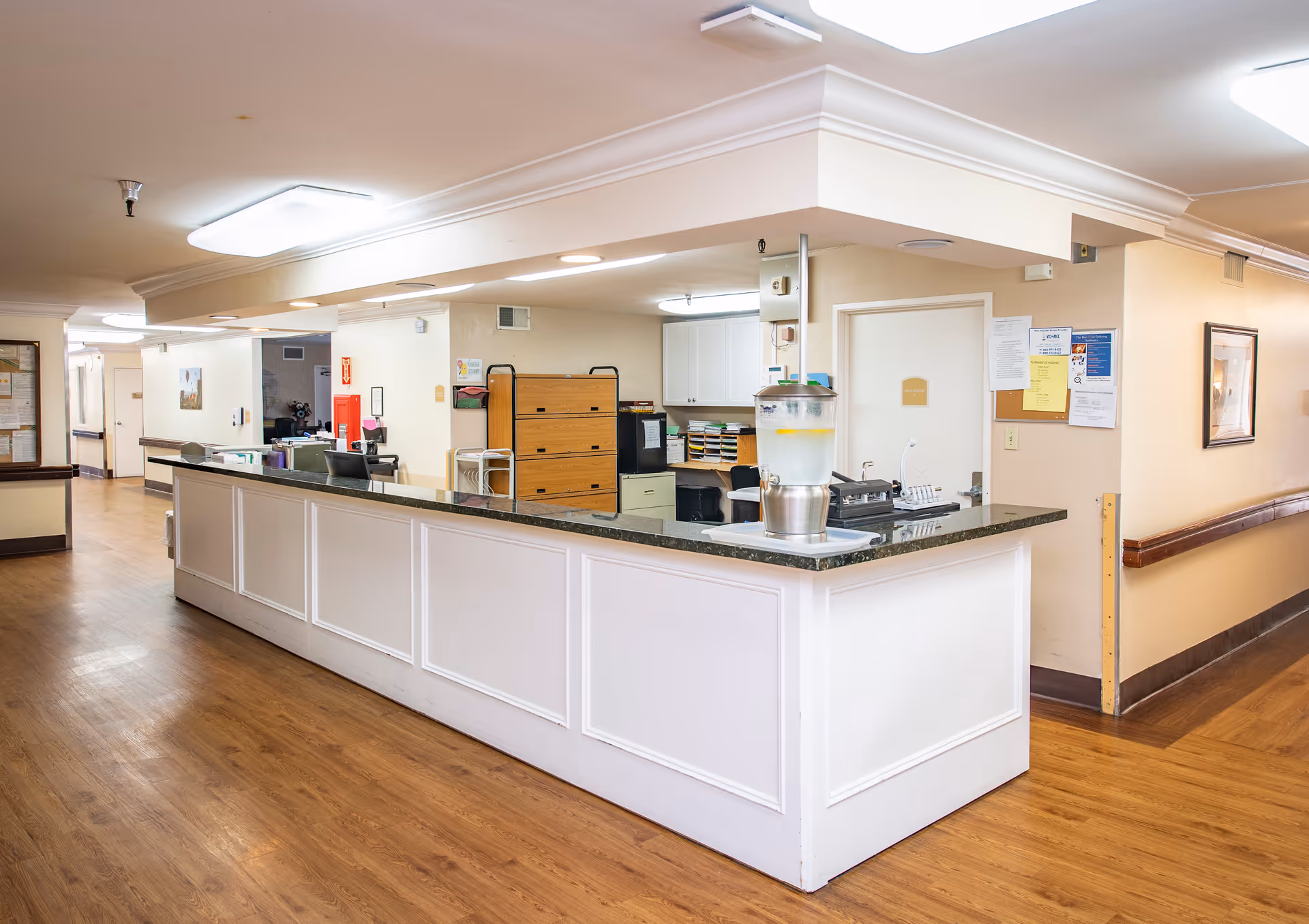 A long white nurses' station counter in the hallway of a senior living facility reception area.
