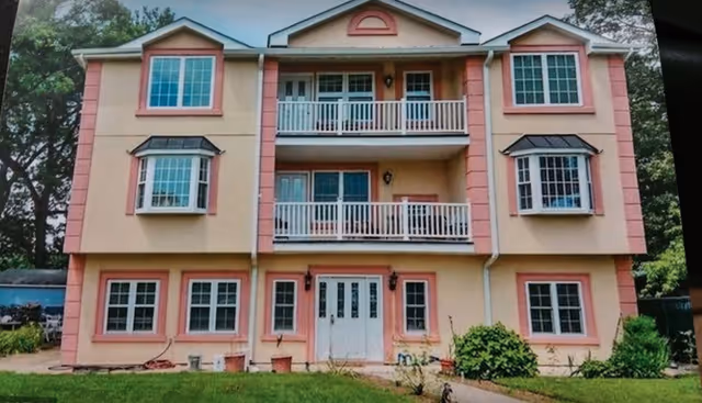 Pink multi-story assisted living building with white balconies and a front entrance.