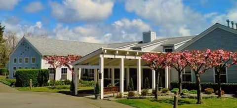 Exterior view of Green Lake Senior Living Ocean Shores with a covered entrance and blooming trees.