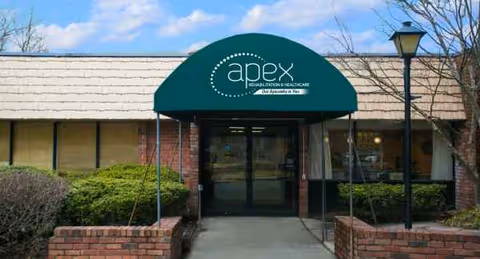 Entrance to Apex Rehabilitation & Care Center with glass doors under a green curved awning.