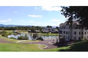 View of a senior living facility named Asbury Place Maryville with a large pond, walking paths, and multiple buildings surrounded by green lawns and trees under a blue sky with some clouds.